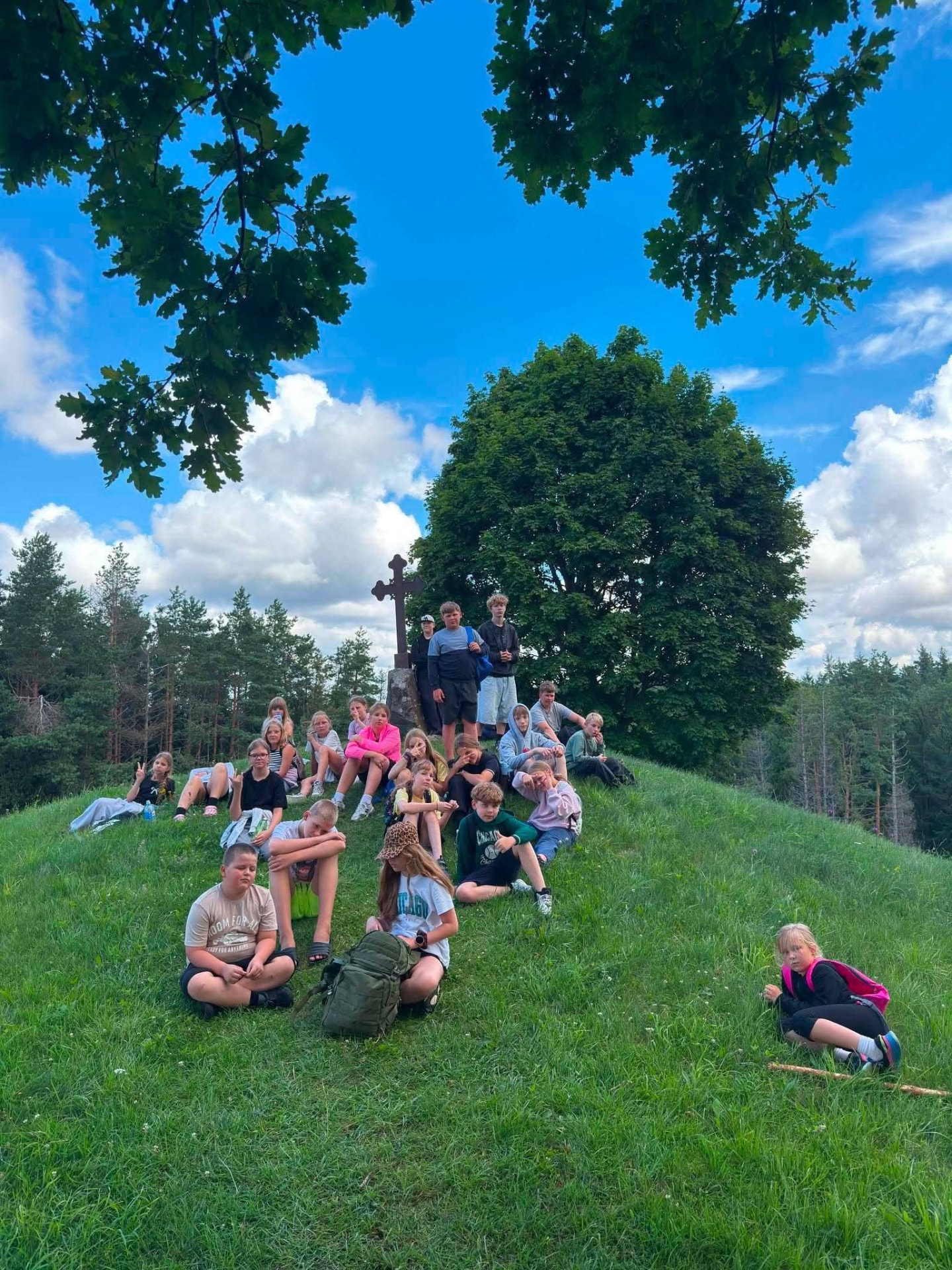 Young people resting on a hillside during an outdoor community activity
